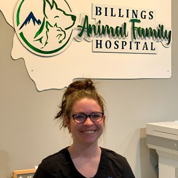 A staff member stands in front of the Billings Animal Family Hospital sign. 