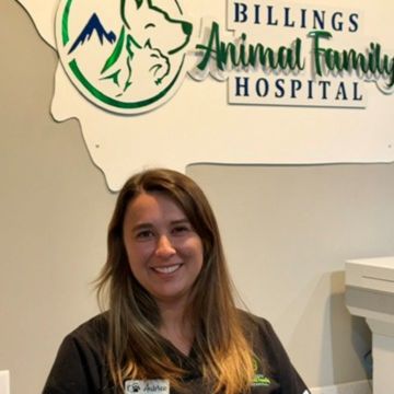 A staff member stands in front of the Billings Animal Family Hospital sign. 