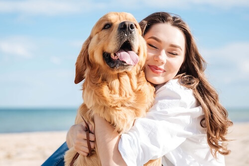 lady hugging dog on the beach